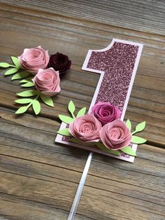 the number one is made out of paper and has pink flowers on top of it