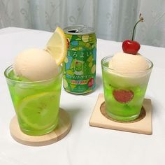 two glasses filled with green liquid and ice cream next to a can of soda