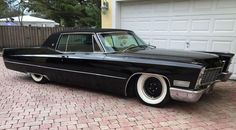 an old black car parked in front of a garage