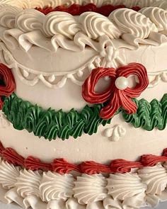 a white cake with red and green icing on it's sides, decorated with holly wreaths