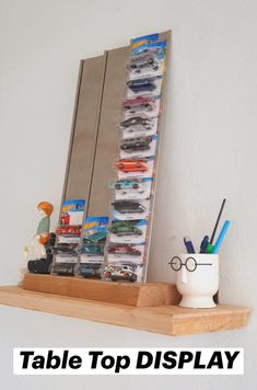 a table top display with toy cars and pencils on it next to a mirror