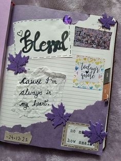 an open journal with writing on it and purple leaves attached to the pages that have been altered