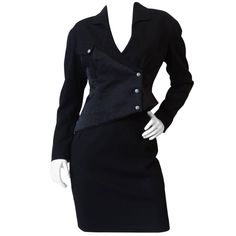 High fashion meets workplace apparel in our incredible 1980s Thierry Mugler suit set! The construction of this jacket is amazing, thick black fabric contrasted with quilted satin. Asymmetrical hemline adds some futuristic flair. Silver snap buttons up the side of the jacket and breast pocket. Sexy basic black pencil skirt, zips up in the back. Marked a size 44, best fits about a Medium. Jacket (44) Shoulder: 19 in Bust: 34 in Waist: 30 in Sleeve: 22 in Length: 22 in Skirt Waist: 28 in Hip: 38 in Asymmetrical Suit, Mugler Suit, Black Skirt Suit, Black Velvet Skirt, Classy Suits, Black Knit Top, Navy Suit, Thierry Mugler, Black Pencil Skirt