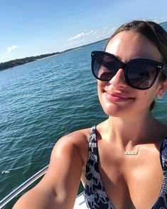 a woman on a boat in the water wearing sunglasses