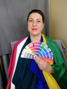 a woman is holding a fan in her hand and she has a color chart on it