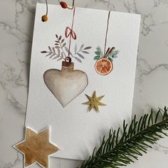 an ornament hanging from a christmas tree next to a card with ornaments on it