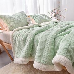 a bed covered in green and white blankets