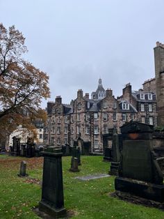 an old cemetery with many headstones in front of a large building on a cloudy day