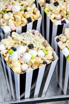 some kind of popcorn with marshmallows and candy on top in striped paper cups