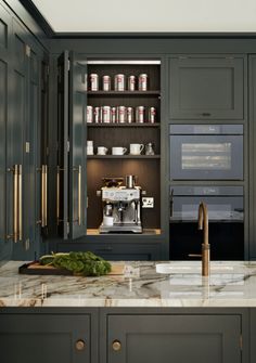 a kitchen with green cabinets and marble counter tops