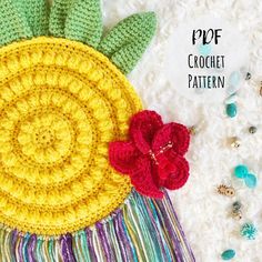 a crocheted pineapple with flowers on it next to beads and other items