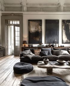 a living room filled with lots of furniture and paintings on the wall above it's windows