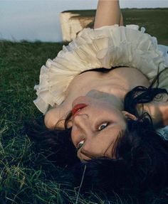 a woman laying on the ground wearing a white dress