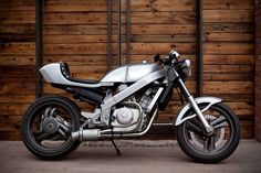 a silver motorcycle parked in front of a wooden wall