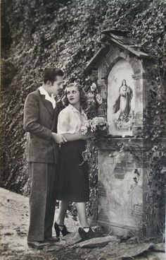 an old black and white photo of a man and woman standing next to a shrine