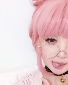 a woman with pink hair and glasses on her face