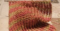 an orange and yellow knitted scarf laying on the ground