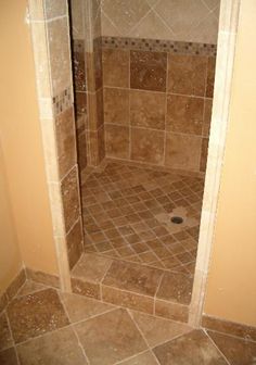 a walk in shower sitting inside of a bathroom next to a tiled floor and walls