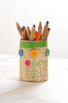 a basket filled with lots of different colored pencils next to some markers and buttons