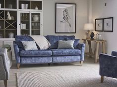 a living room with blue couches and pictures hanging on the wall above it's coffee table