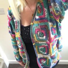 a woman with blonde hair wearing a multicolored crocheted jacket