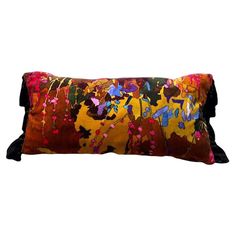 a decorative pillow with colorful paint splattered on the front and back, sitting on a white background