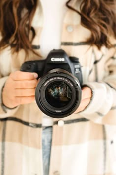 a woman holding a camera in her hands and taking a photo with it's lens