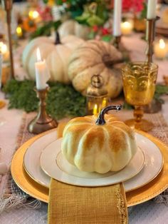 a white pumpkin sitting on top of a plate next to candles and other decor items