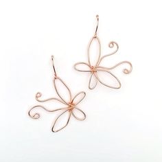 two pairs of earrings are shown on a white surface