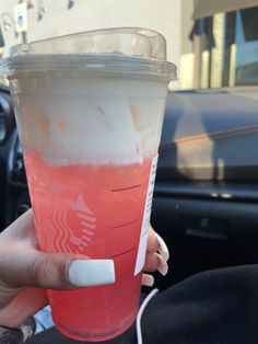 a person holding up a pink drink in their hand with white nail polish on it