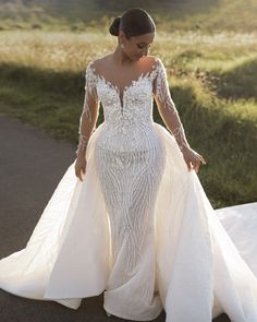 a woman in a wedding dress is walking down the road with her hand on her hip