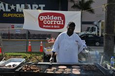 a man grilling hamburgers on an outdoor grill in front of a golden corral sign