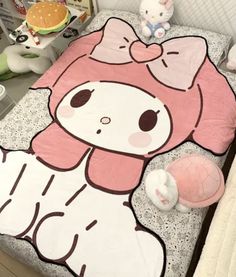 a bed with a hello kitty comforter and stuffed animals on the floor next to it