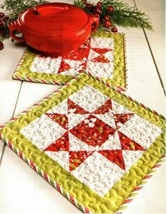 two quilted placemats sitting on the floor next to a potted plant