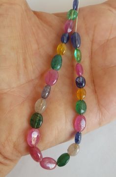 a hand holding a strand of multicolored glass beads