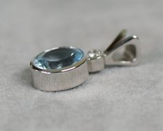 A bright blue genuine aquamarine from Brazil is set in 14k white gold. The aquamarine is bezel set and above it is a bezel set diamond and a solid tapered bail. This is an eye clean, well cut genuine aquamarine AA color. Metal: 14k white gold Weight: 3.76 carats natural aquamarine Measures: 12x10mm oval Weight: .11 carat round brilliant diamond G color VS1 clarity 3mm Pendant measures: 1 inch length 1/2 inch wide and weighs 4.84 grams Chain not included Aquamarine is a member of the beryl family Modern Blue Topaz Jewelry With Bezel Setting, Silver Aquamarine Jewelry With Bezel Setting, Stowe Vt, Aquamarine Colour, Bezel Set Ring, Special Necklace, White Gold Pendant, Dainty Pendant, Tourmaline Necklace