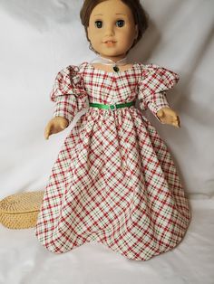 the doll is wearing a red and white checkered dress with a green belt around her waist