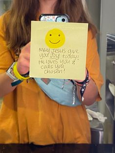 a woman holding up a note with a smiley face on it