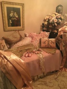 a bed covered in pink and gold sheets next to a chair with flowers on it