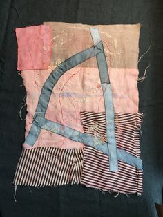 an old piece of cloth with different colored strips and lines on it, sitting on top of a black surface