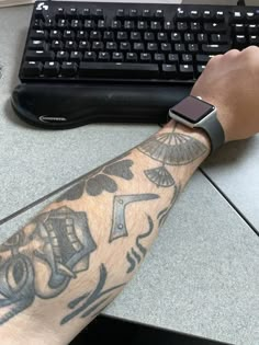 a man's arm with a tattoo on it next to a keyboard and mouse