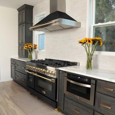 a kitchen with an oven, stove and sunflowers in vases on the counter