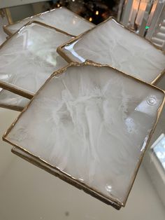 three white and gold square dishes sitting on a counter