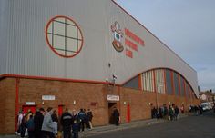 a group of people standing in front of a building with an orange and white stripe on it