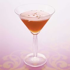 a glass filled with liquid sitting on top of a table next to a pink wall