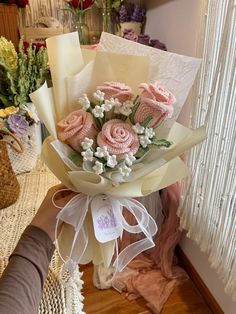 a bouquet of pink roses is wrapped in white paper and sitting on a table next to other flowers