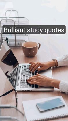 a woman is typing on her laptop while sitting at a table with a cup of coffee