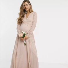 a pregnant woman in a long dress holding flowers