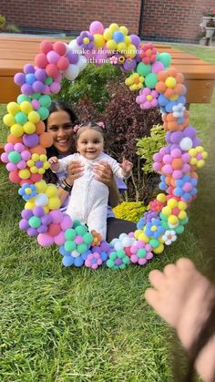 two women and a baby are sitting in front of a photo frame made out of balloons