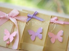 three small bags with pink and purple butterflies on them, tied to twine ribbons